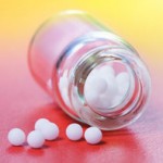 Close view of homeopathic medication - small white balls in glass bottle